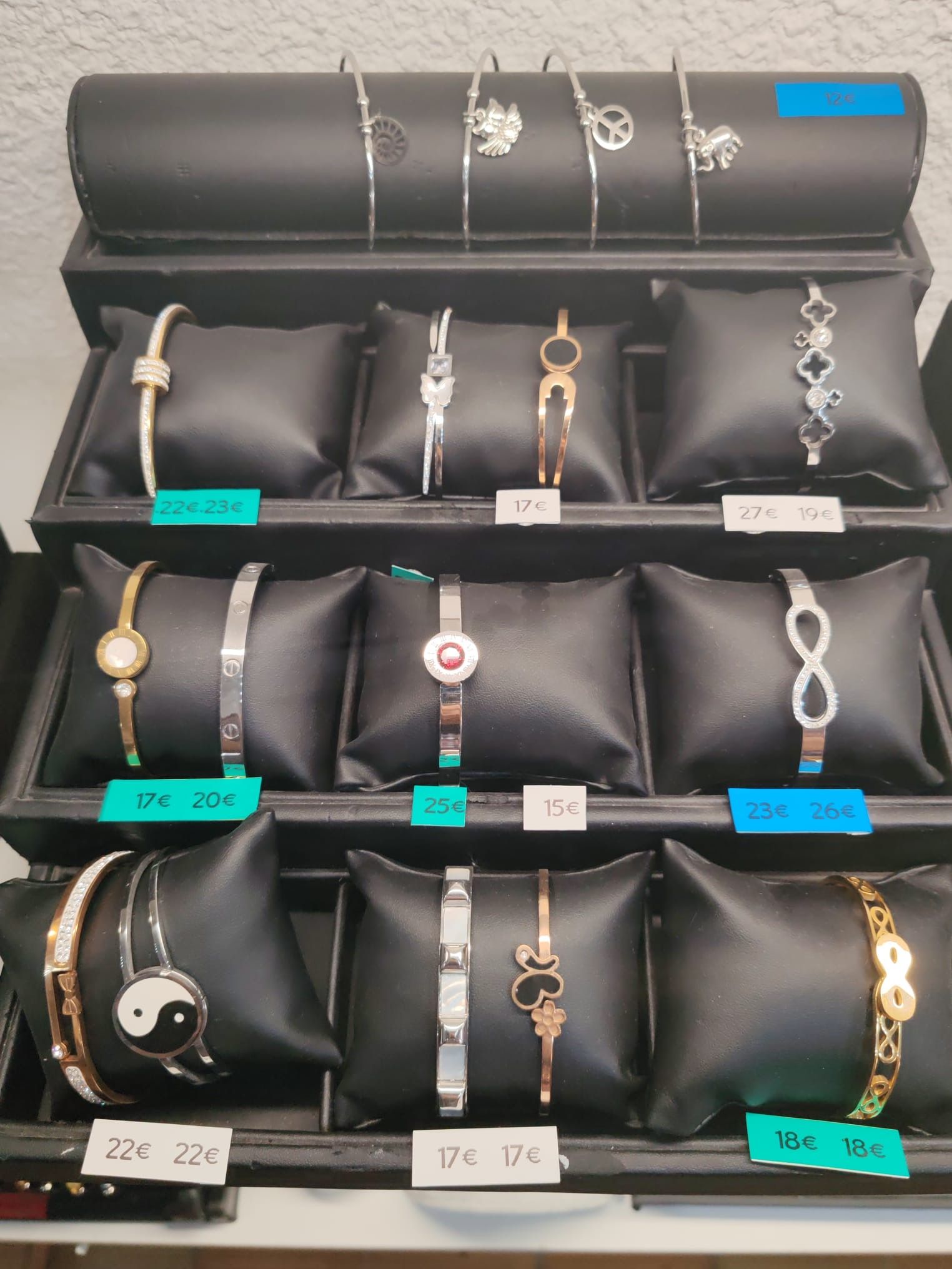 Présentation de bracelets dorés et argentés sur des coussins noirs.