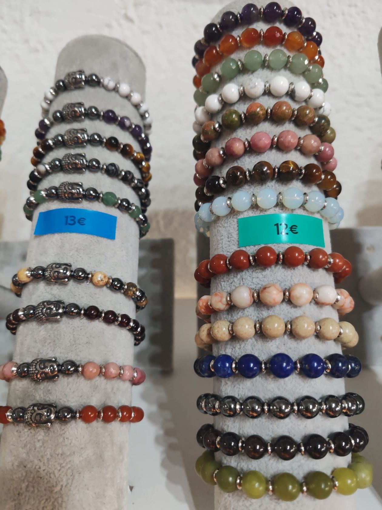 Sélection de bracelets en perles et pierres naturelles, présentés sur des supports d’exposition, avec étiquettes de prix.