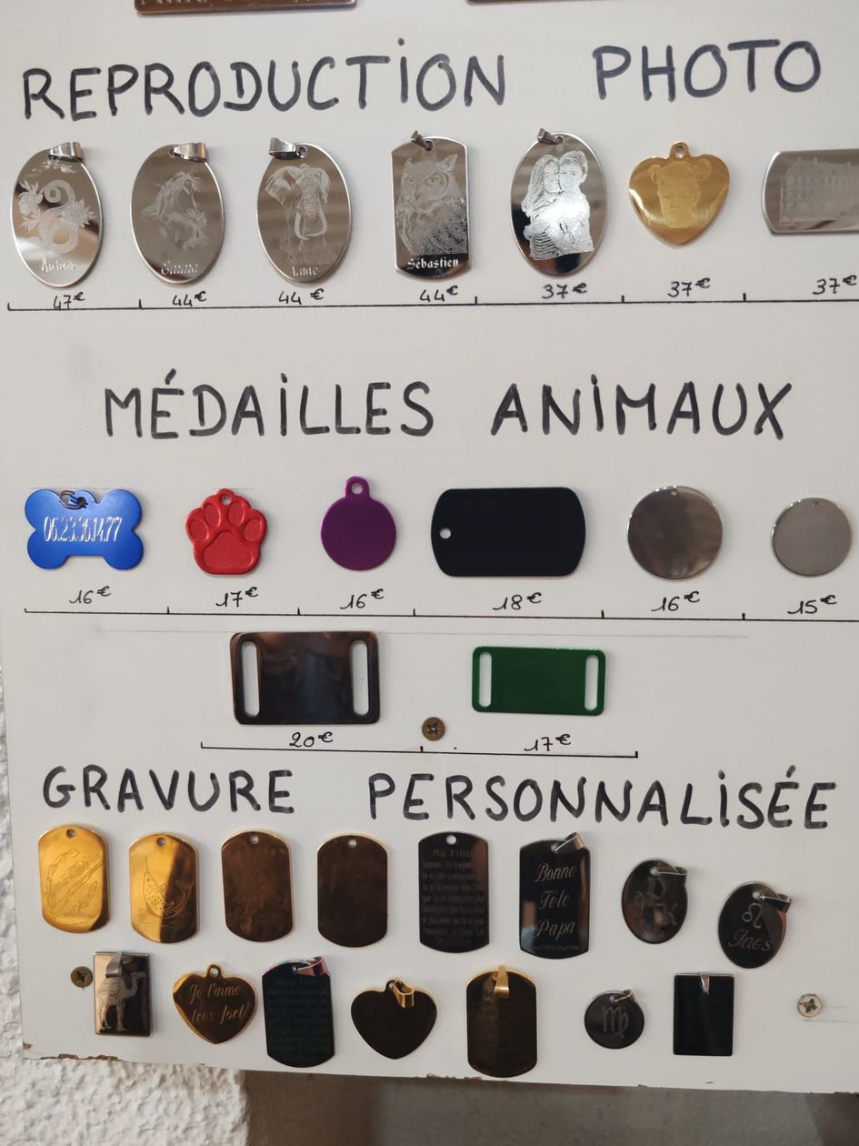 Exemple de présentation de médailles personnalisées pour animaux de compagnie et d'étiquettes gravées fixées sur un tableau blanc.