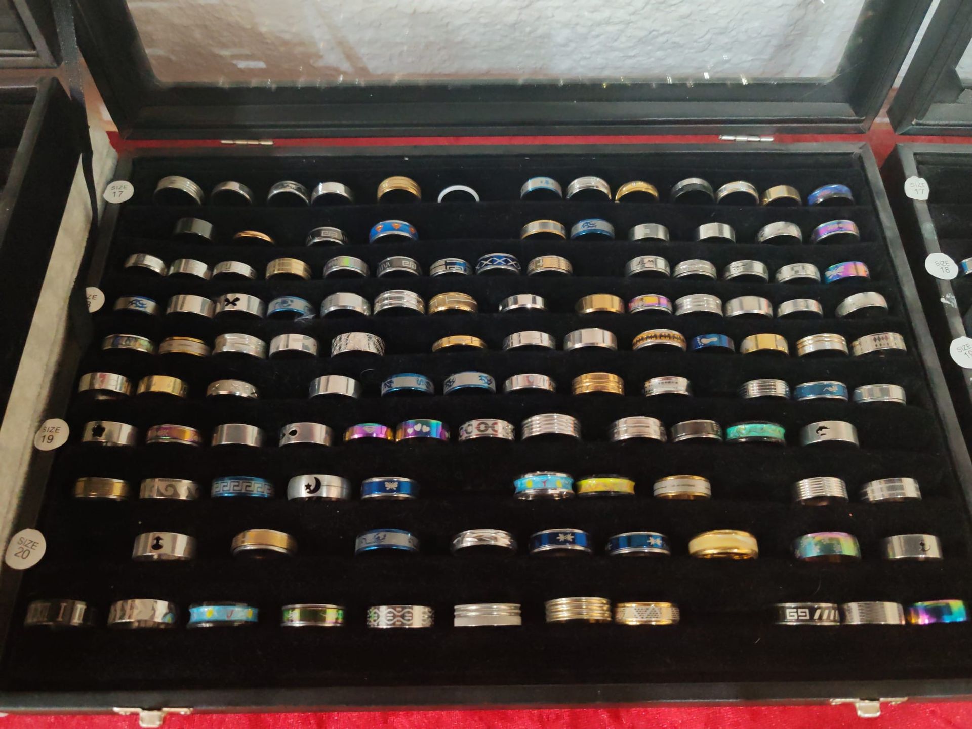 Coffret à bijoux ouvert avec des rangées de bagues colorées présentées dans des compartiments.