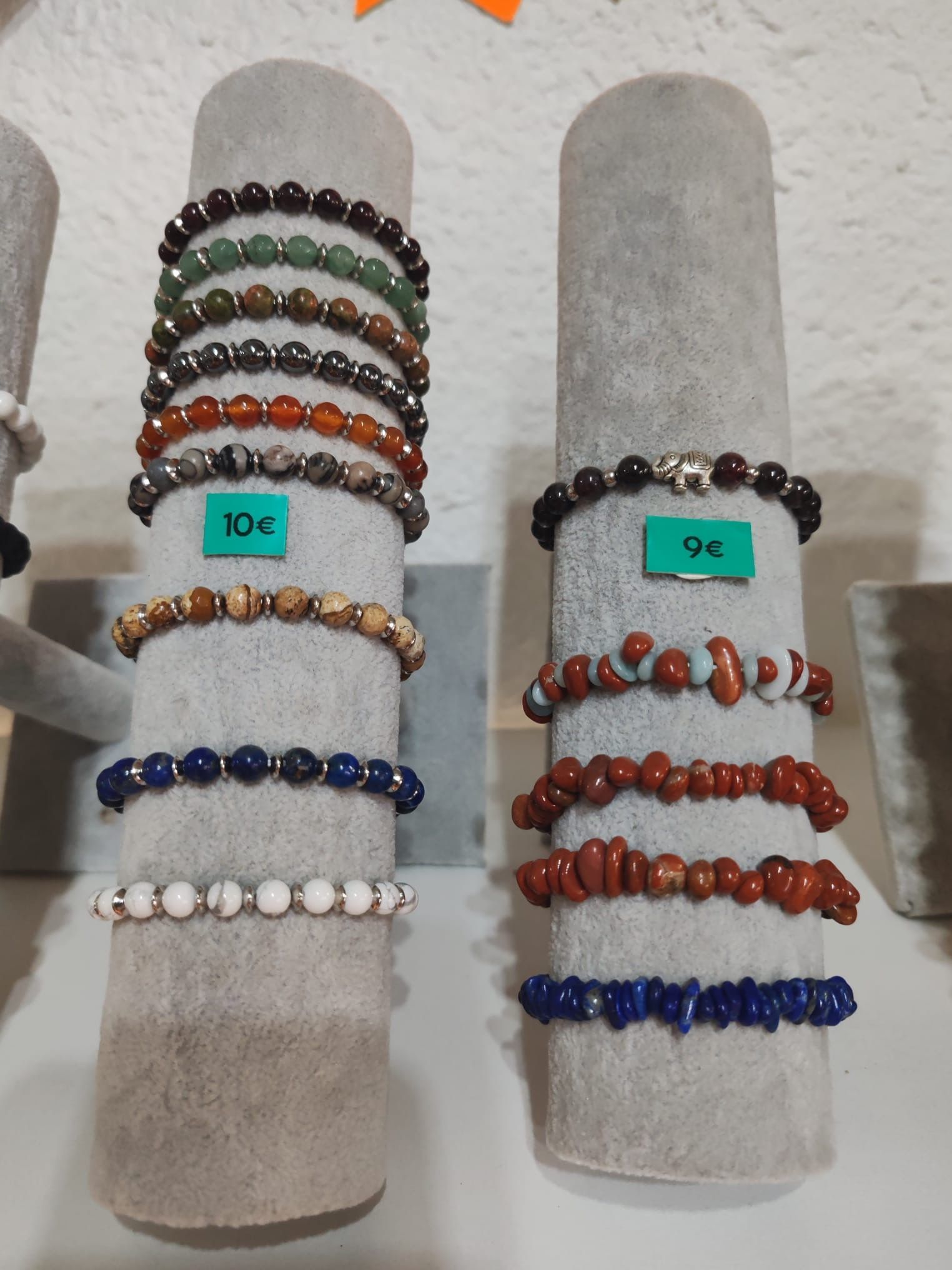 Sélection de bracelets en perles et pierres naturelles, présentés sur des supports d’exposition, avec étiquettes de prix.