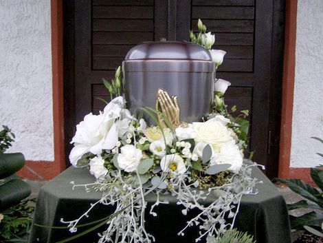 Eine Urne ist von weißen Blumen auf einem Tisch umgeben