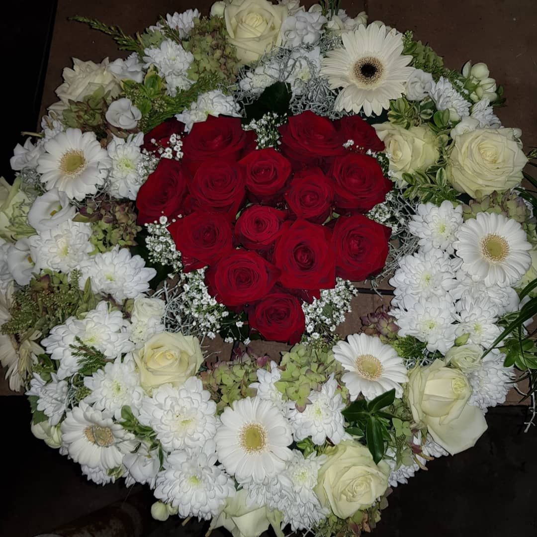 Ein Kranz aus weißen Blumen mit roten Rosen in der Mitte