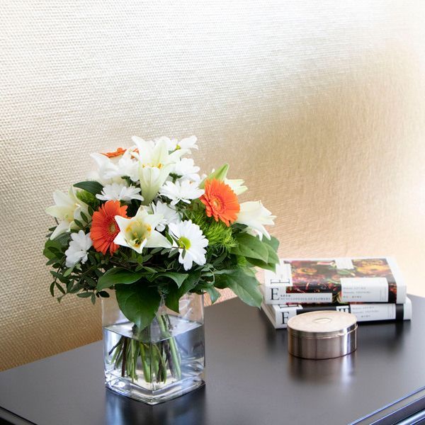 Eine Vase mit Blumen steht auf einem Tisch neben einem Stapel Bücher