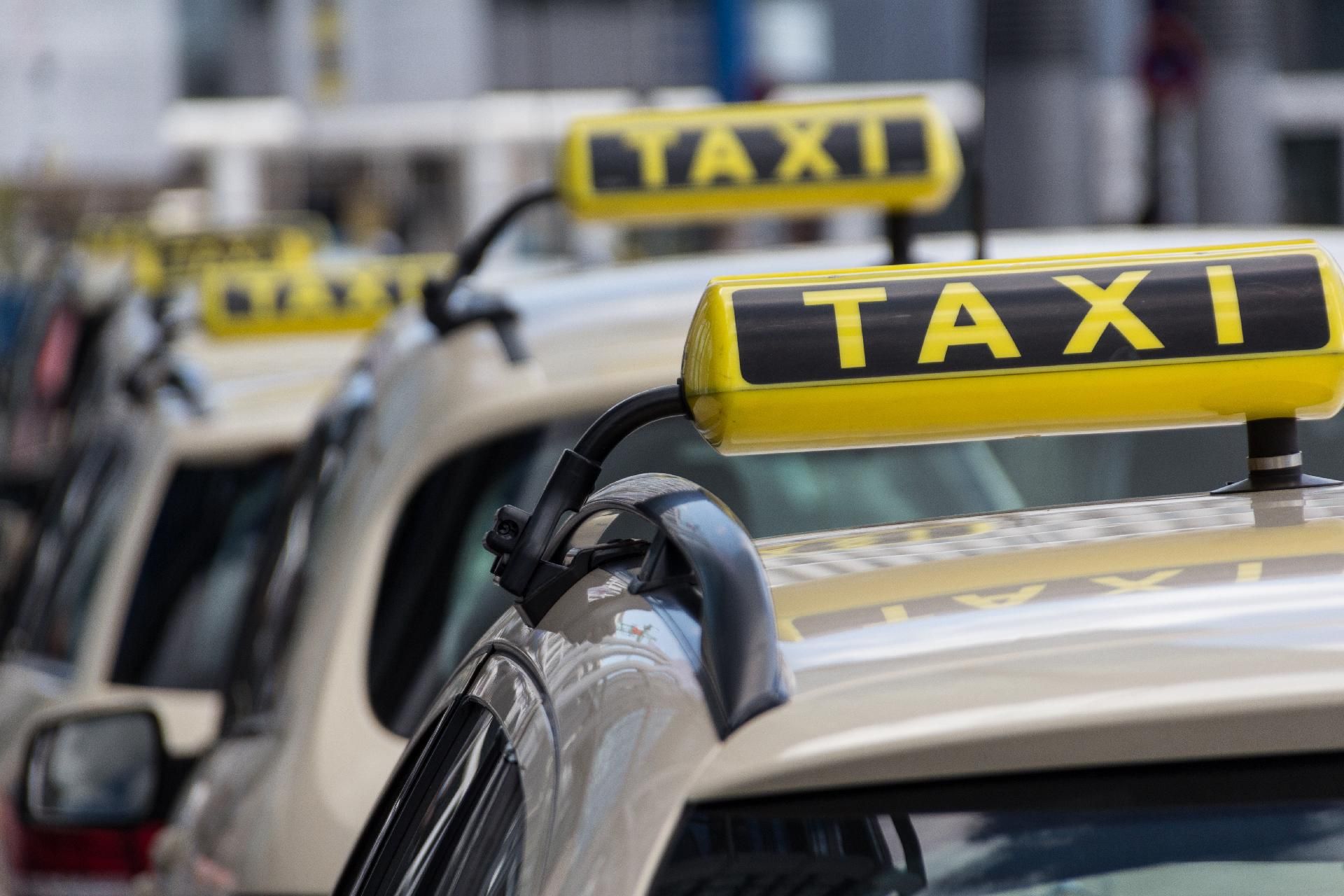 Nahaufnahme von gelben Taxi-Dachschildern einer wartenden Fahrzeugschlange.
