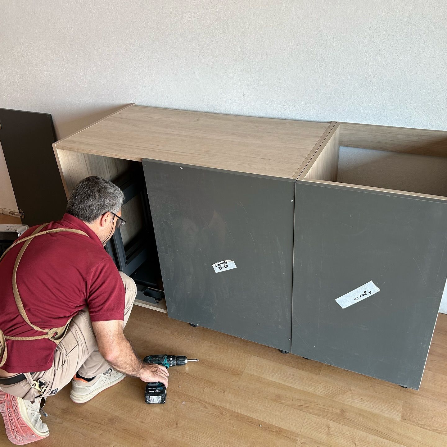 Un hombre está trabajando en un armario con un taladro.