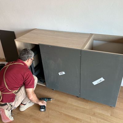 Un hombre está trabajando en un armario con un taladro.