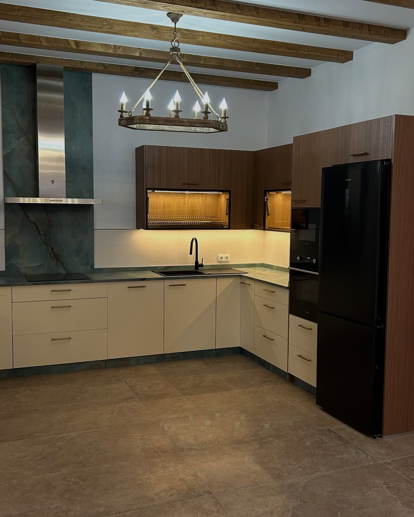 Una cocina con gabinetes blancos y un refrigerador negro.