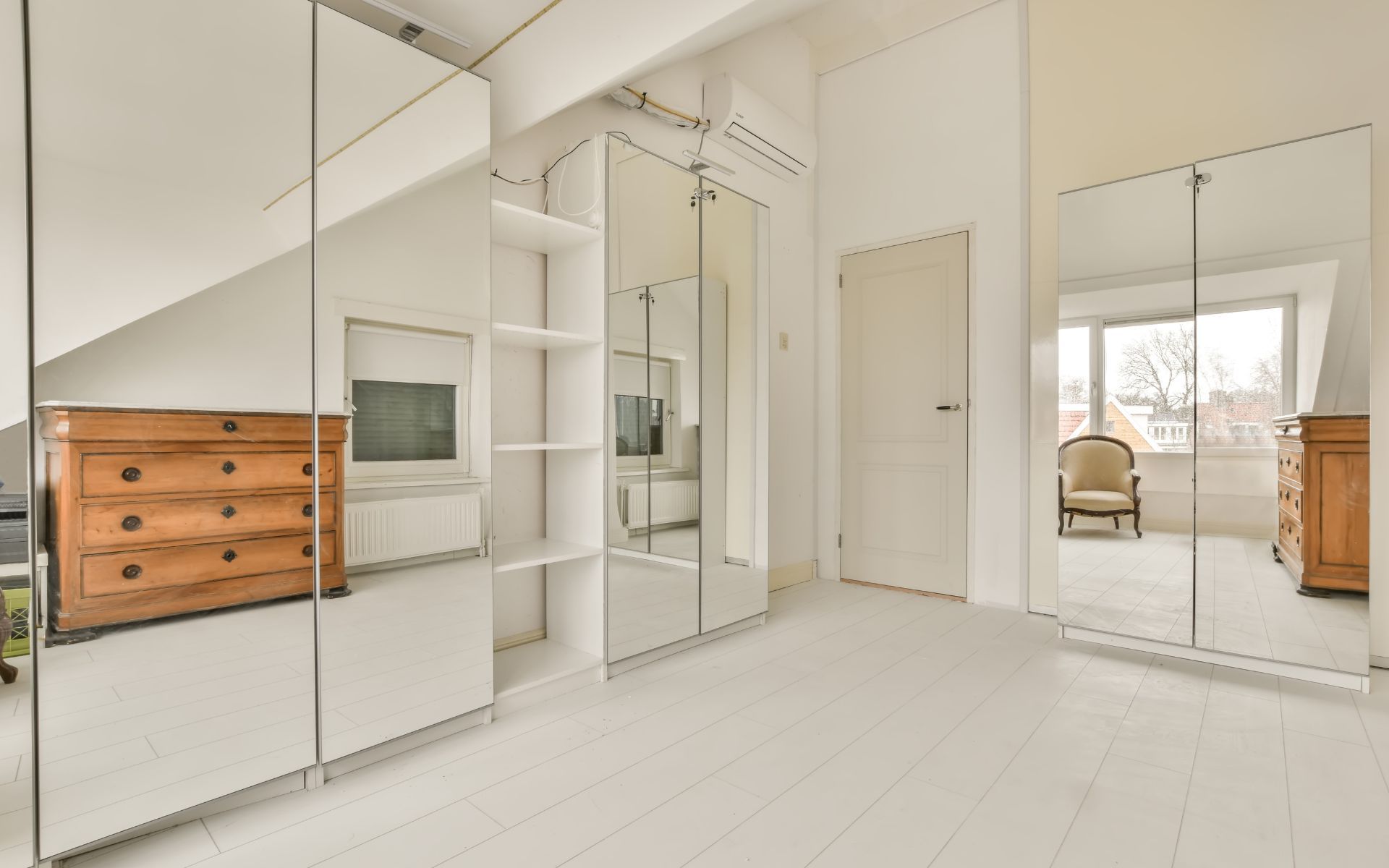 Un dormitorio con muchos espejos y una cómoda.