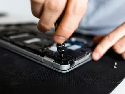 Una persona está arreglando una computadora portátil con un destornillador.