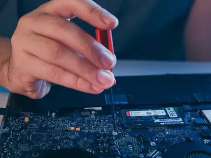 Una persona está arreglando una computadora portátil con un destornillador.