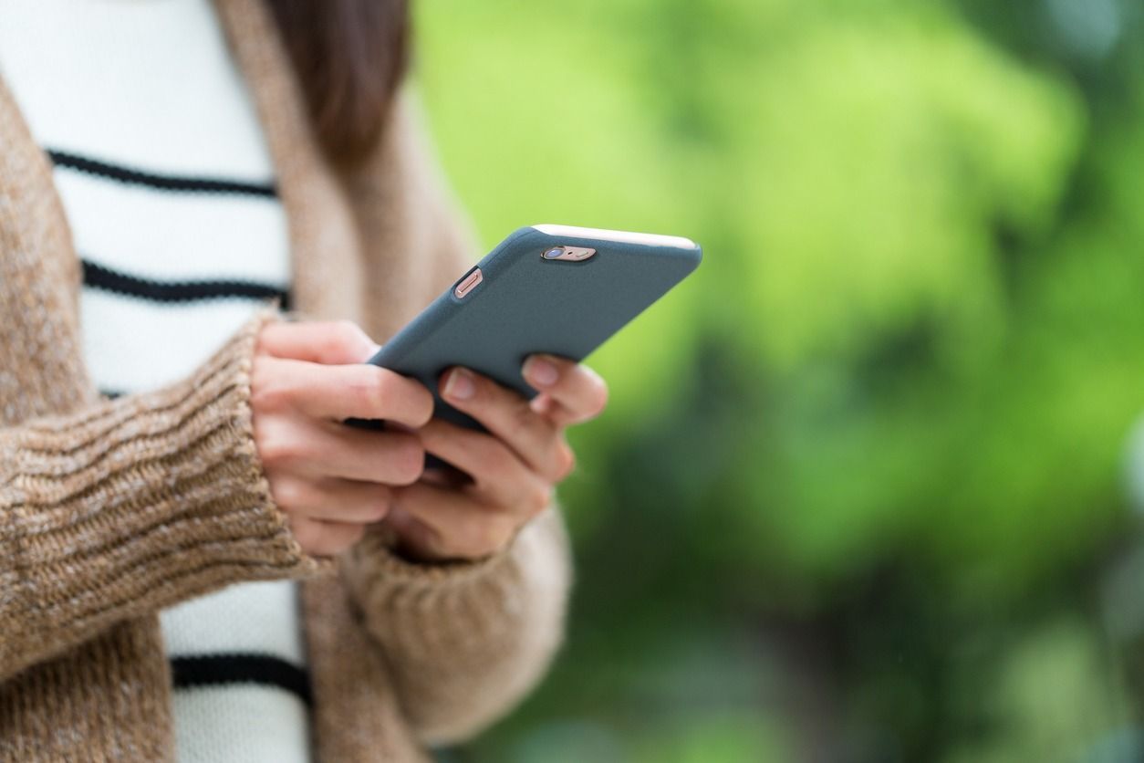 Una mujer sostiene un teléfono celular en sus manos.