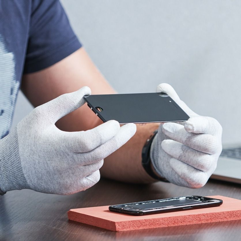 Un hombre con guantes blancos sostiene un teléfono celular.