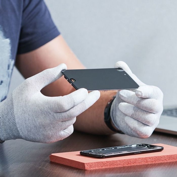 Un hombre con guantes blancos sostiene un teléfono celular.