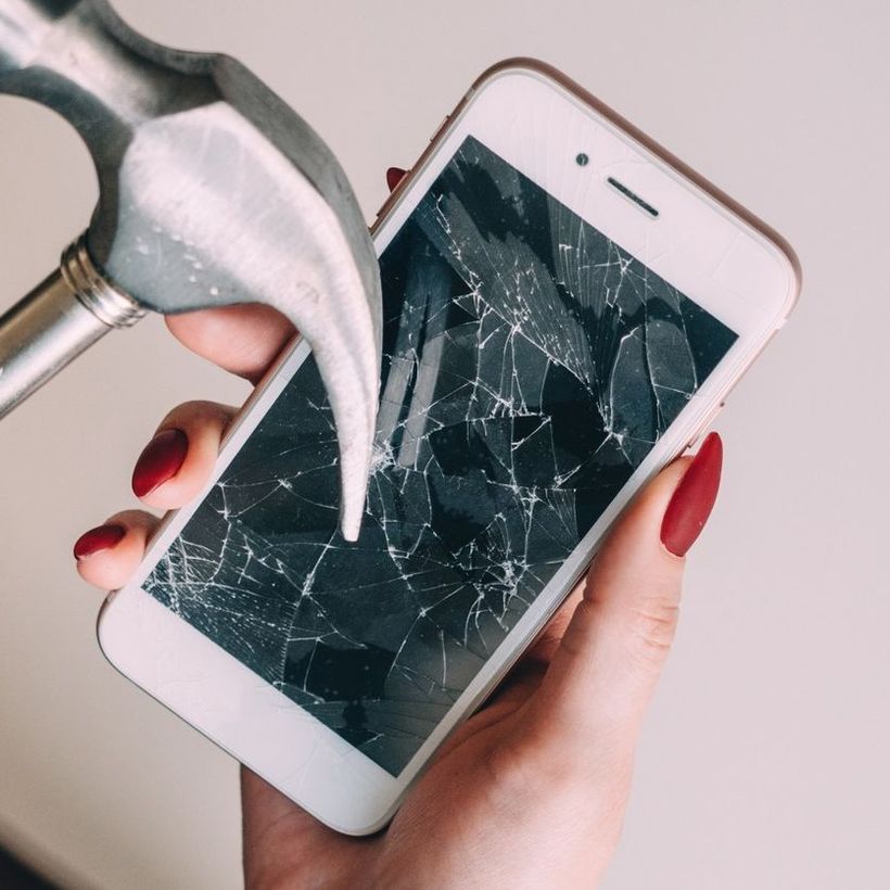 Una persona sostiene un teléfono celular con la pantalla rota.