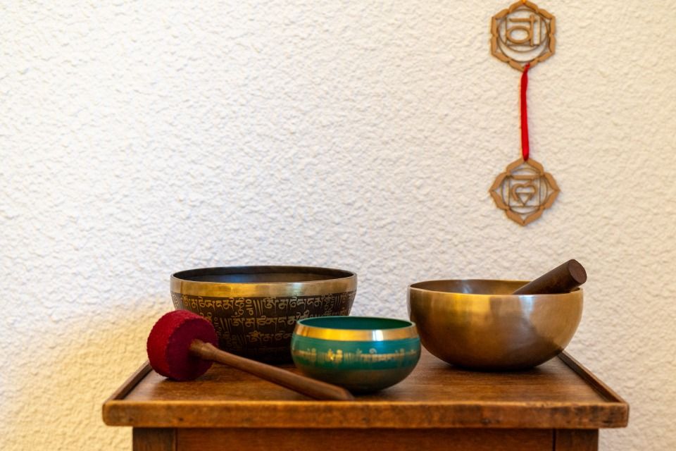 Trois bols chantants sur une table en bois, avec un maillet et des décorations murales.