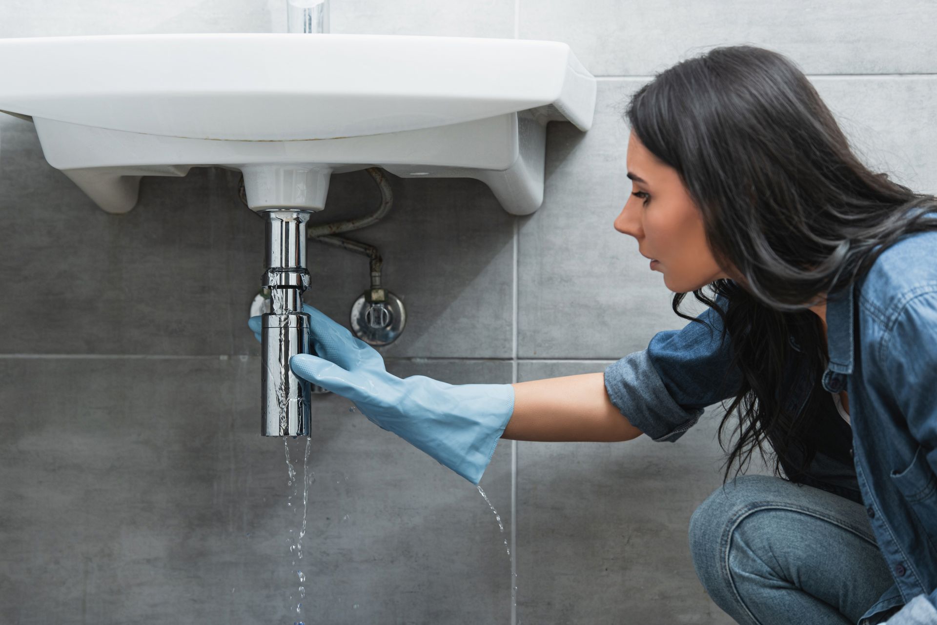 Femme essayant de réparer une fuite d'eau d'un lavabo