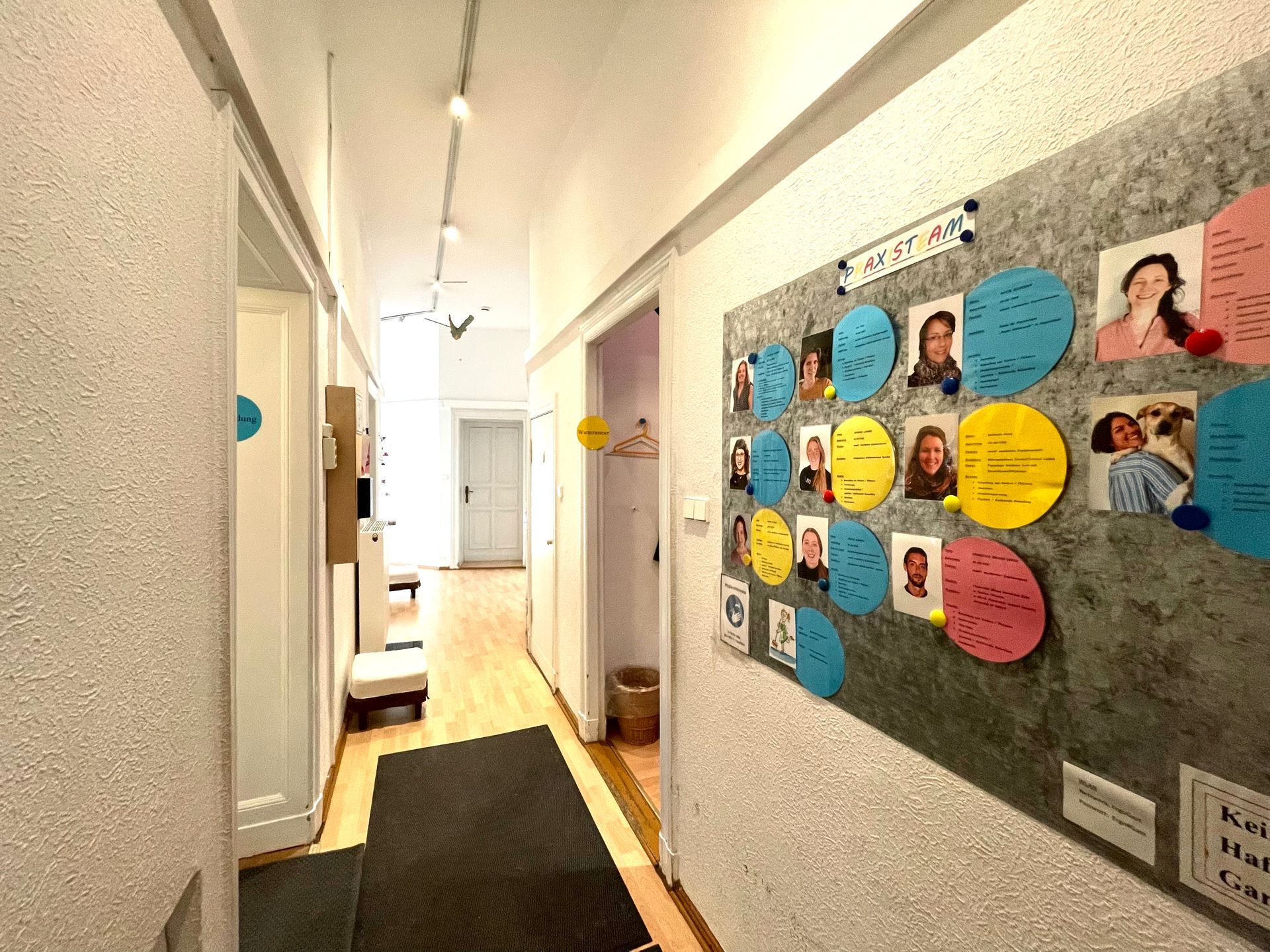 Flur mit Anschlagtafeln, Klassenzimmertüren und Blick in einen Speisesaal am Ende.