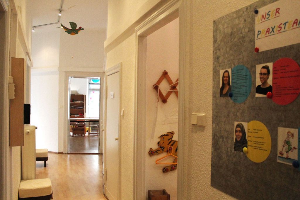 Flur mit Anschlagtafeln, Klassenzimmertüren und Blick in einen Speisesaal am Ende.