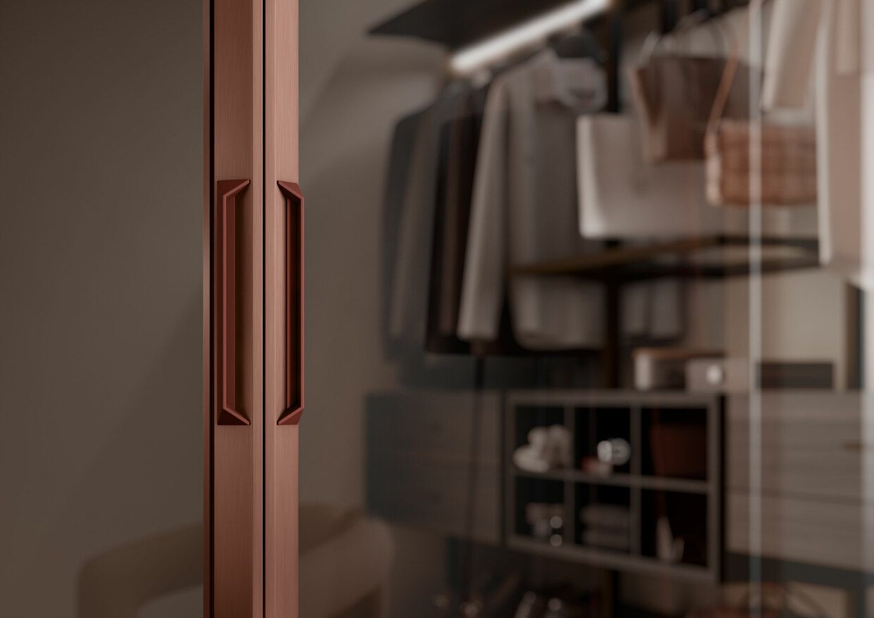 Eine Nahaufnahme einer Glastür in einem Schrank, an der Kleidung hängt. Wohntrend NRW Raumplus