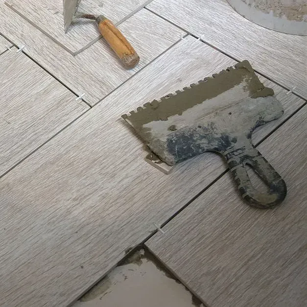 Una espátula está colocada sobre un suelo de baldosas al lado de una paleta.
