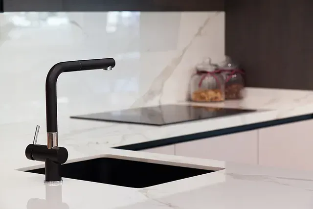 Un fregadero de cocina con un grifo negro y un horno de leña.