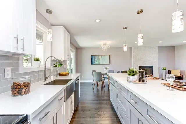 Una cocina con gabinetes blancos, un fregadero y una isla grande.