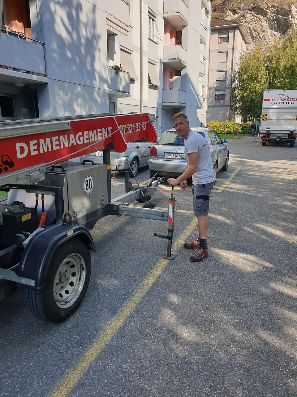 Un homme se tient à côté d'une caravane sur laquelle est écrit déménager