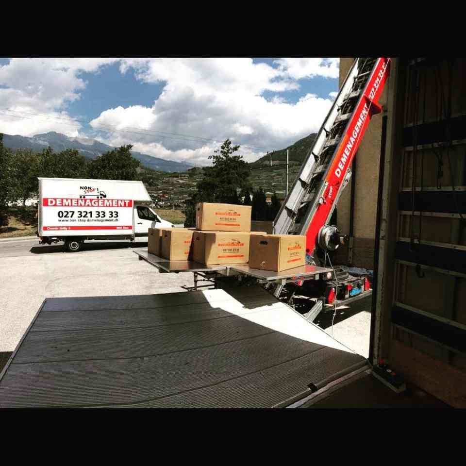 Un camion d'une entreprise de déménagement est chargé de cartons et d'une échelle.
