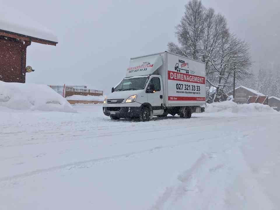 Un camion blanc roule sur une route enneigée.