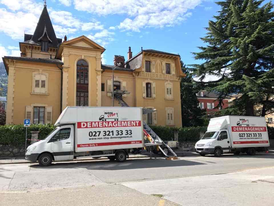 Deux camions de déménagement sont garés devant un grand bâtiment.