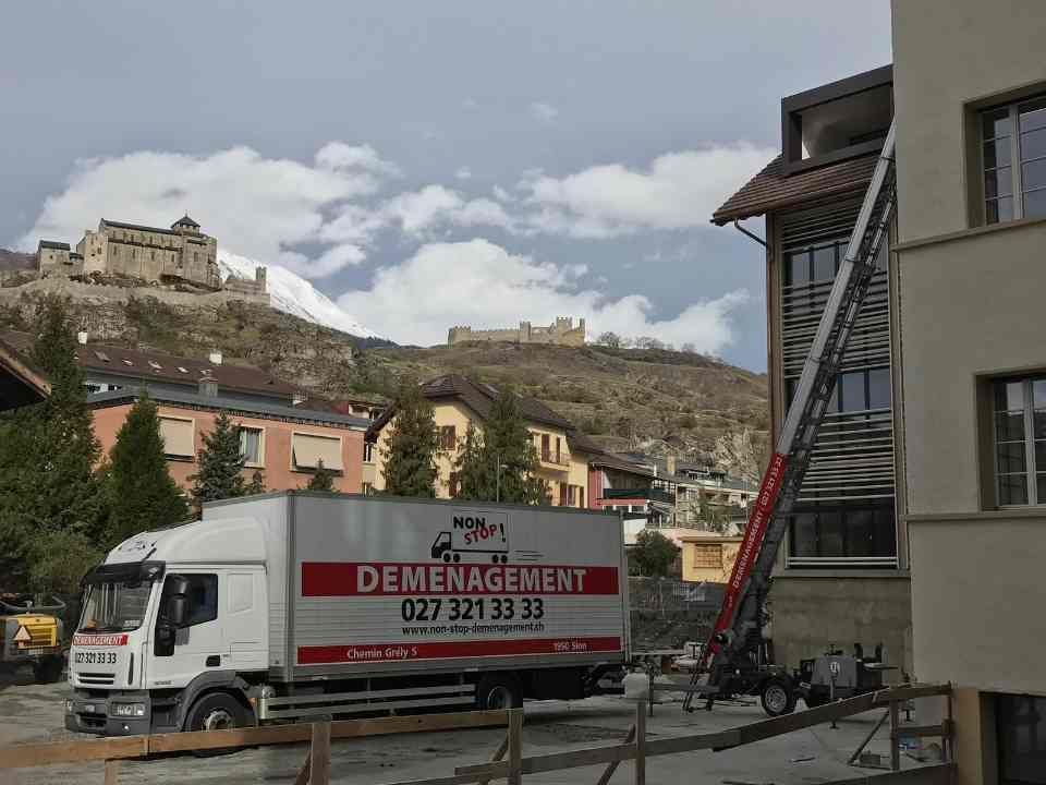 Un camion de déménagement blanc est garé devant un immeuble