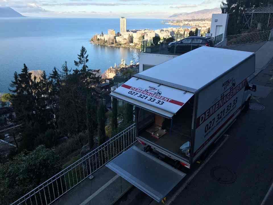 Un camion de déménagement est stationné sur le bord de la route près d'un plan d'eau.