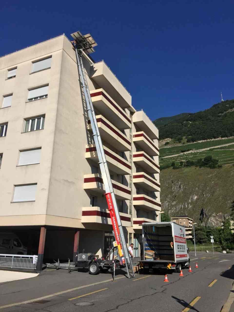 Un grand bâtiment avec une échelle au sommet de l'entreprise de déménagement Non-Stop Déménagement Sàrl