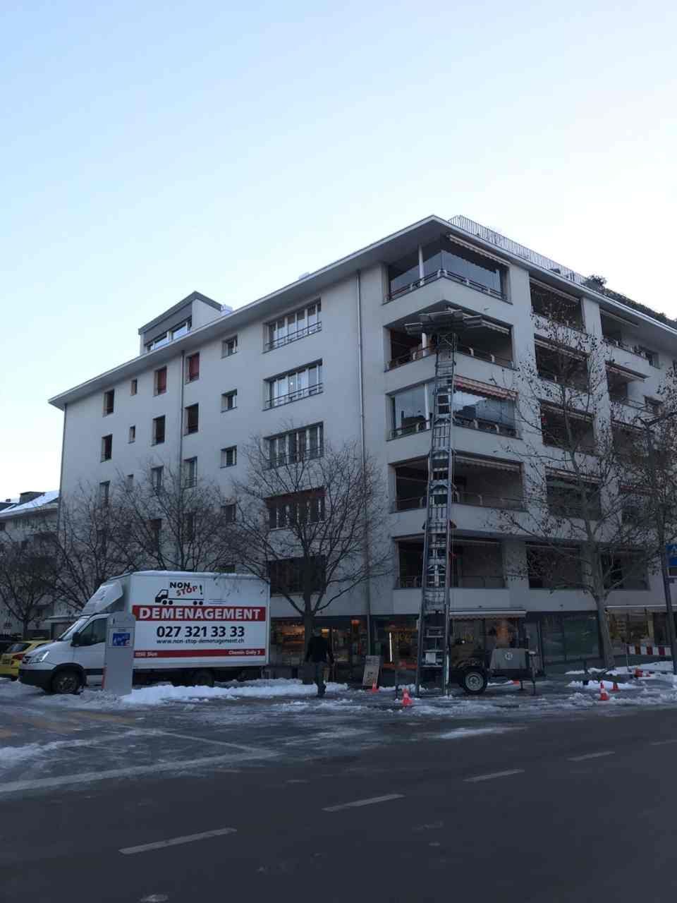 Une camionnette blanche est garée devant un grand immeuble.