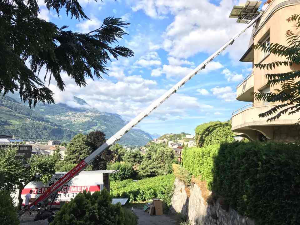 Une grue soulève une boîte au sommet d'un bâtiment