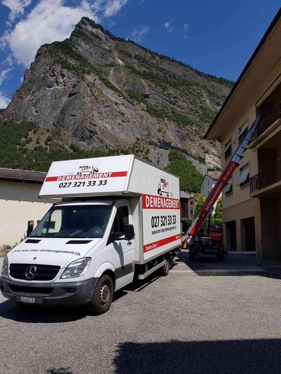 Une camionnette Mercedes est garée devant un bâtiment avec une montagne en arrière-plan