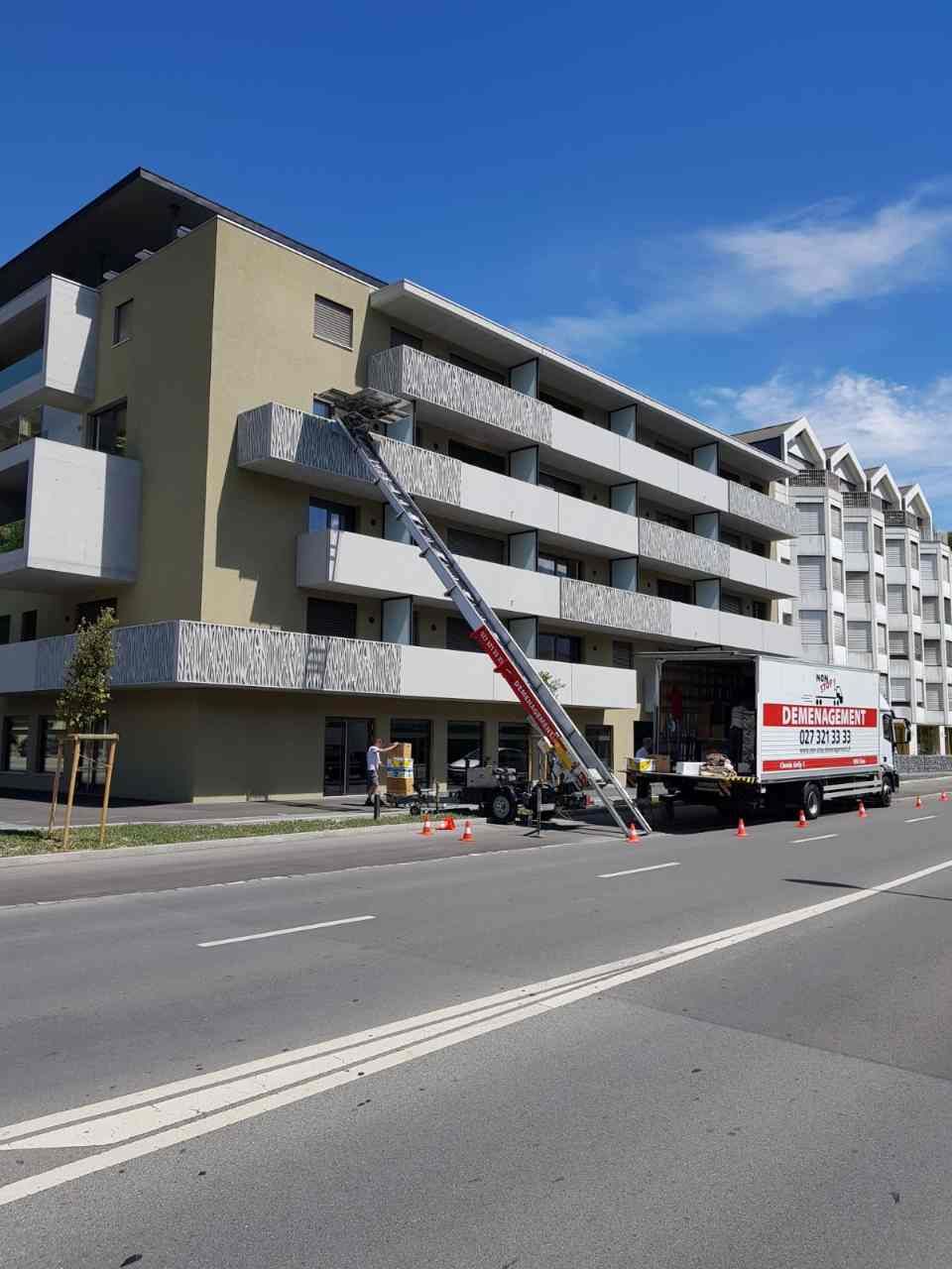 Un grand bâtiment avec un camion de déménagement garé devant