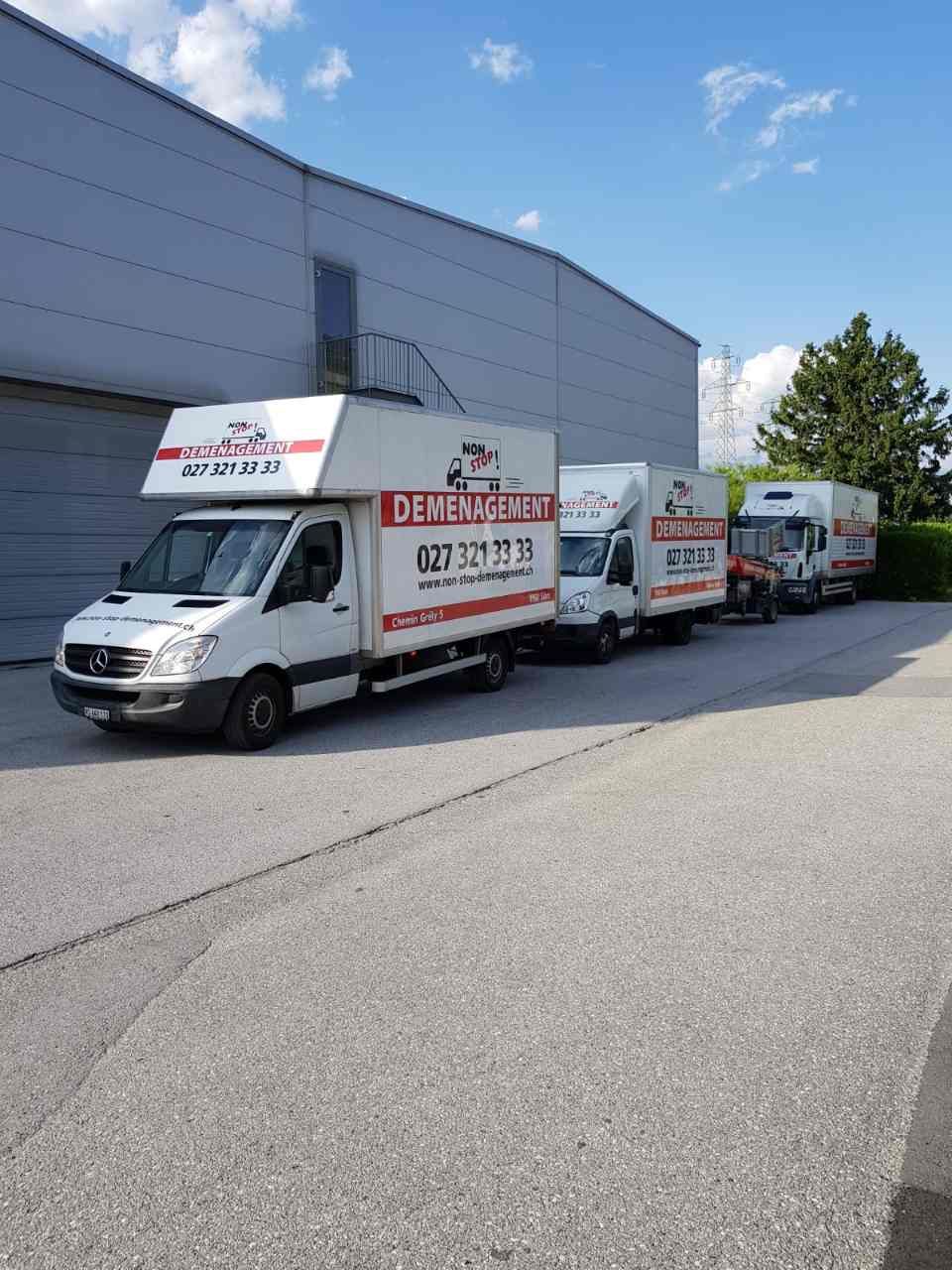 Une rangée de fourgons de déménagement garés devant un immeuble