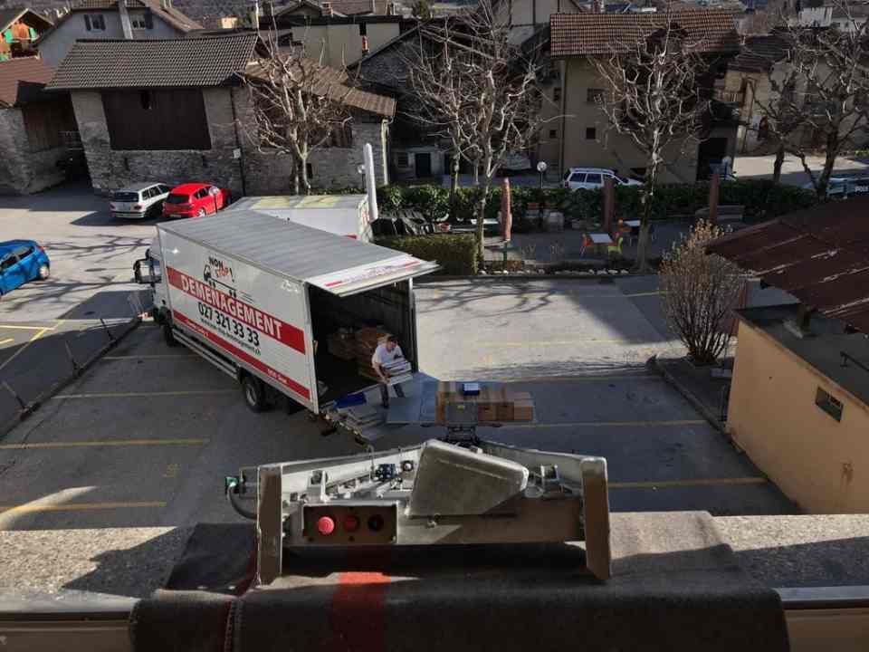 Un camion de déménagement est garé dans un parking à côté d'un immeuble.