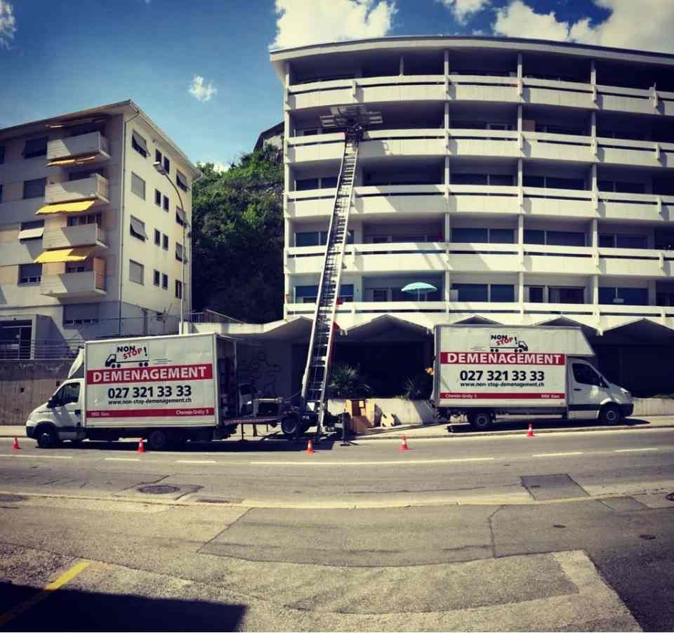 Deux camions de déménagement sont garés devant un immeuble