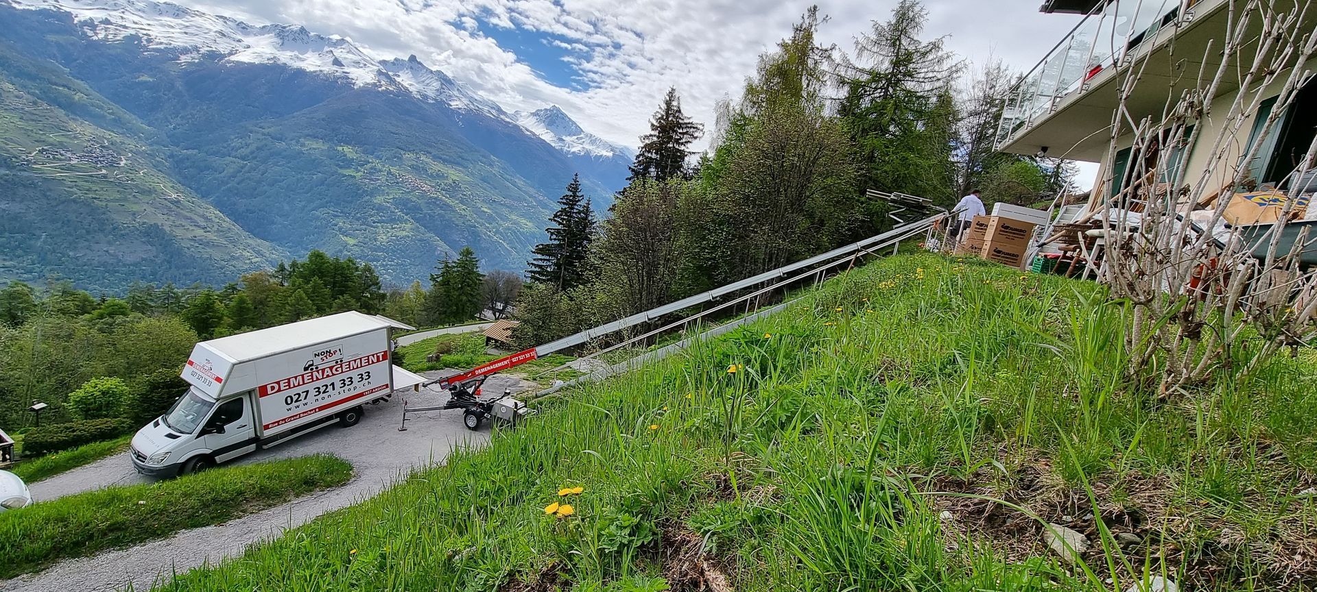 Une camionnette blanche descend une colline avec des montagnes en arrière-plan.