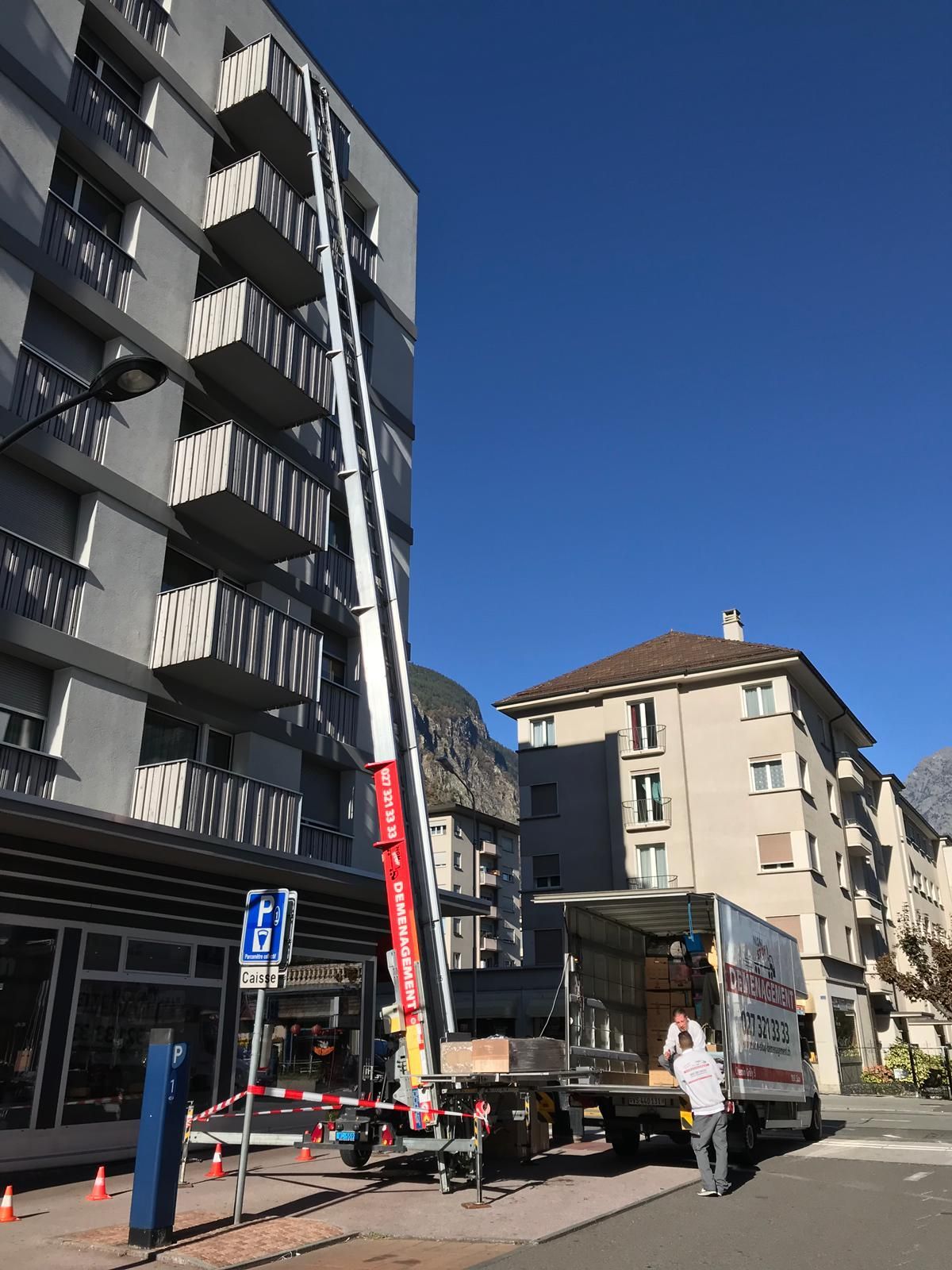 Un camion de déménagement est garé devant un grand immeuble