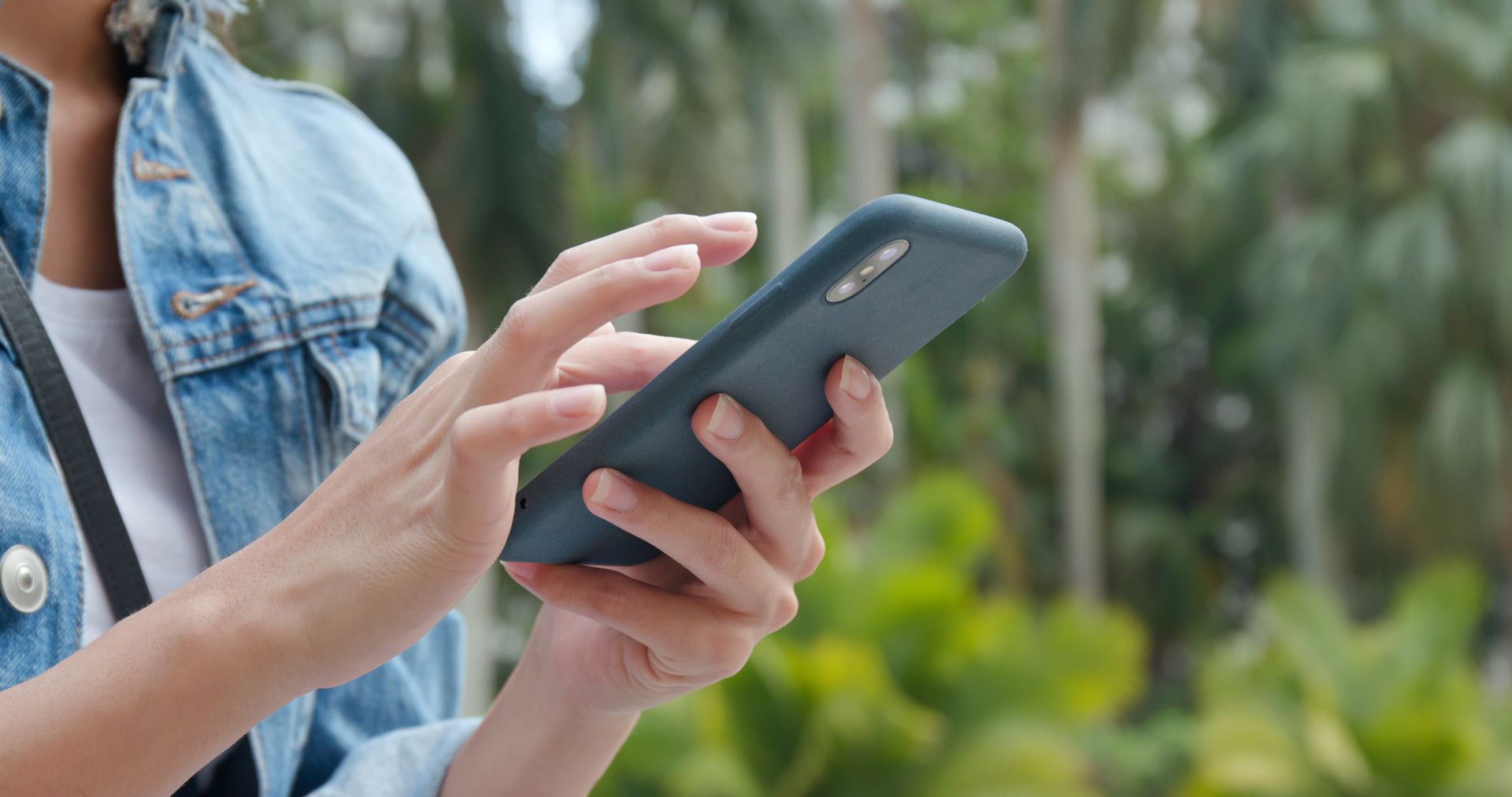 Eine Frau hält ein Mobiltelefon in ihren Händen.