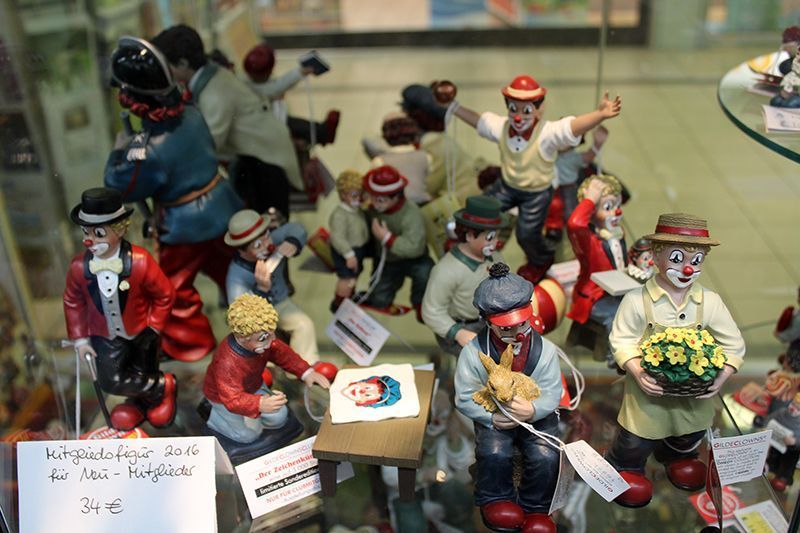 In einer Glasvitrine ist eine Gruppe von Clownfiguren ausgestellt.