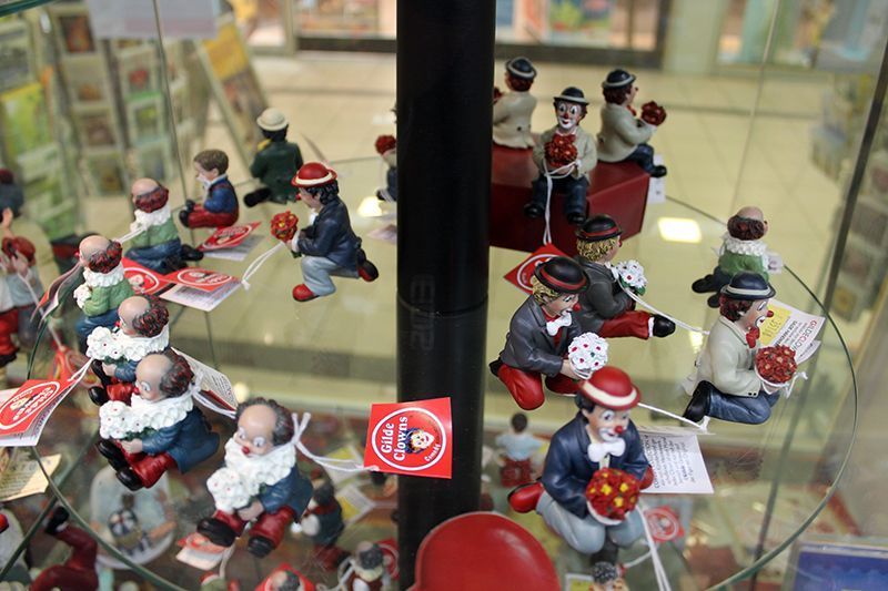 Eine Ausstellung von Clownfiguren auf einem Glasregal