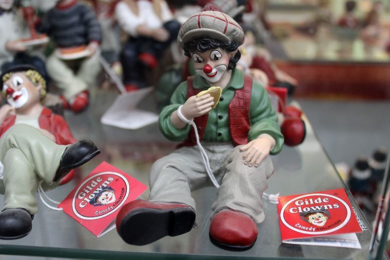 Eine Gruppe von Clownfiguren sitzt auf einem Glasregal.