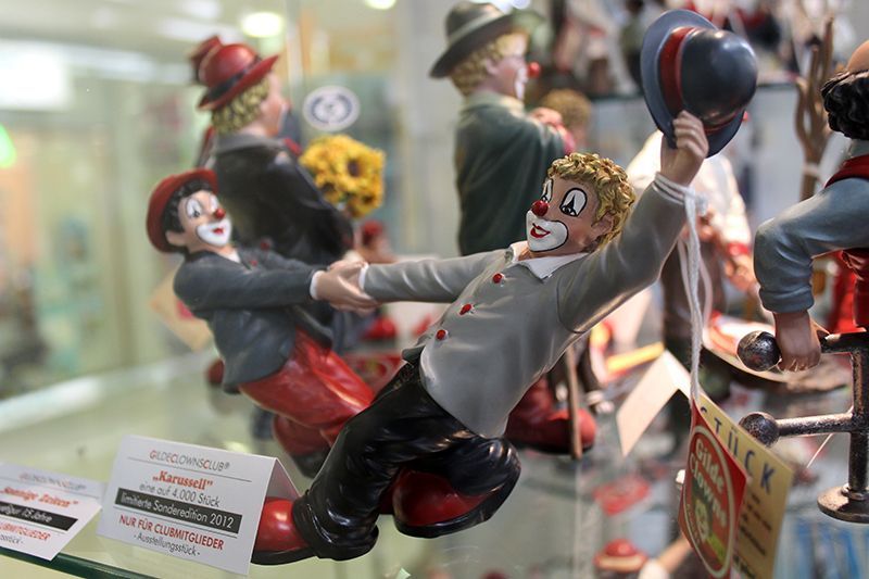 Eine Gruppe von Clownfiguren sitzt auf einem Glasregal.