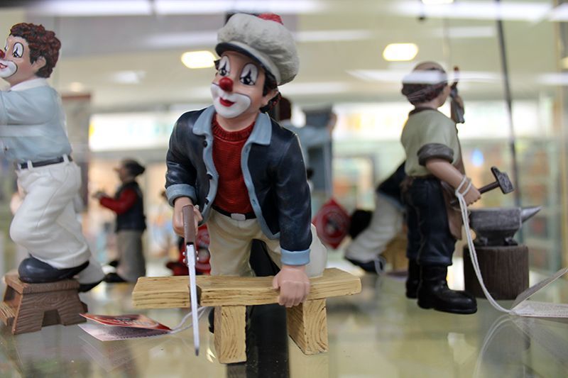 In einer Glasvitrine ist eine Gruppe von Clownfiguren ausgestellt.