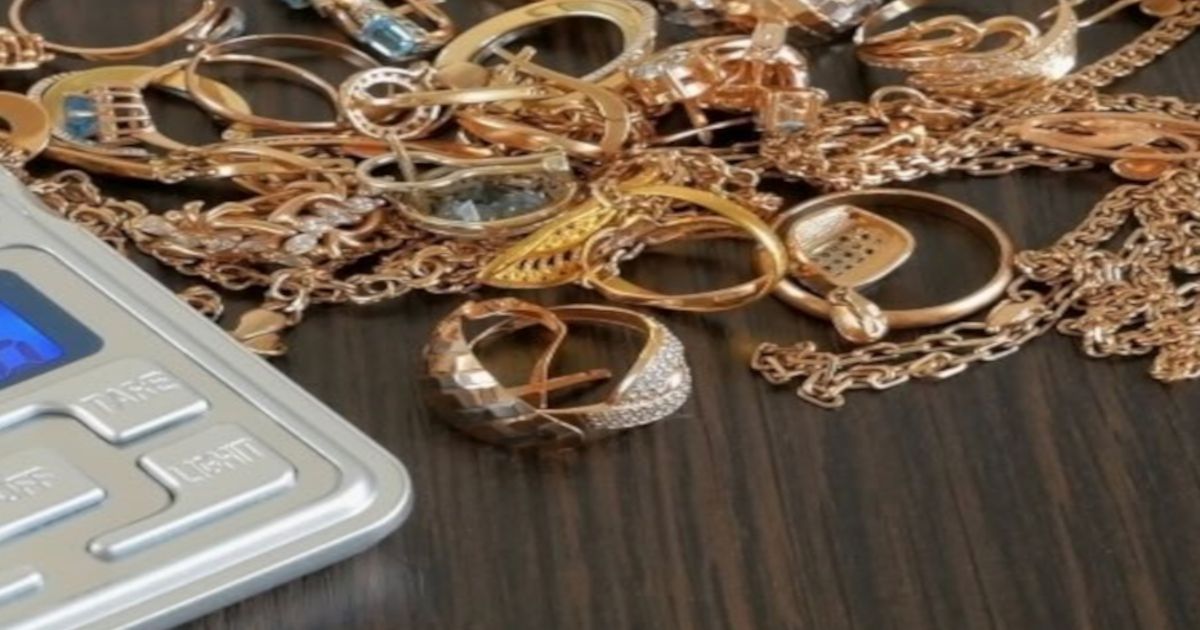 Goldene Ringe und Ketten liegen auf einem Holztisch und daneben liegt ein silberner Rechner für den Goldankauf.